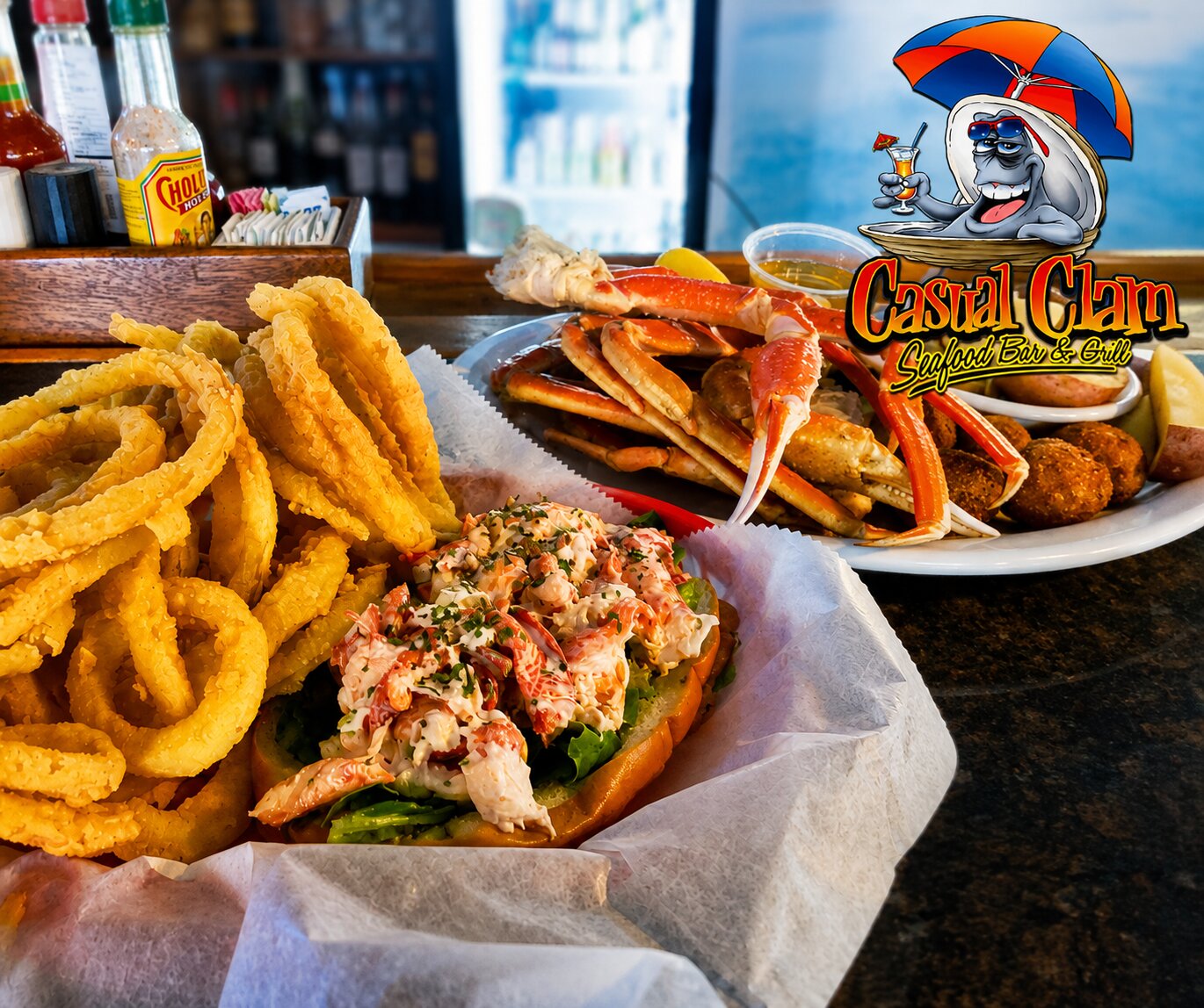 Casual-Clam-Seafood-Bar-Grill-seafood-spread-featuring-a-lobster-roll-onion-rings-crab-legs-and-the-restaurant-logo-in-St.-Petersburg-Florida